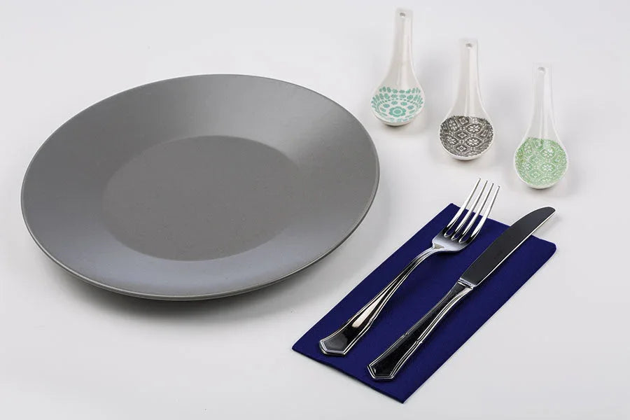 Guardanapos de Mesa Azuis Dobrados 1-8 PPP 40x40cm juntos a um prato e talheres sobre uma mesa decorada.