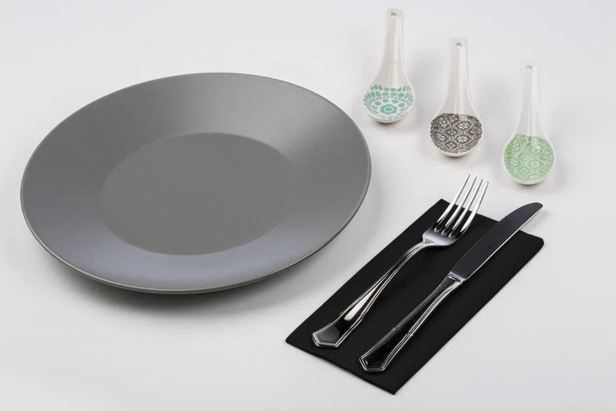 Guardanapos de Mesa Pretos Dobrados 1-8 PPP 40x40cm com prato cinza e talheres em uma mesa organizada.