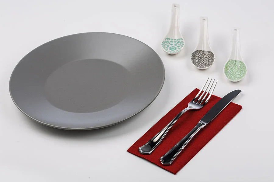 Guardanapos de Mesa Bordô Dobrados 1-8 PPP 40x40cm em mesa com prato e talheres.