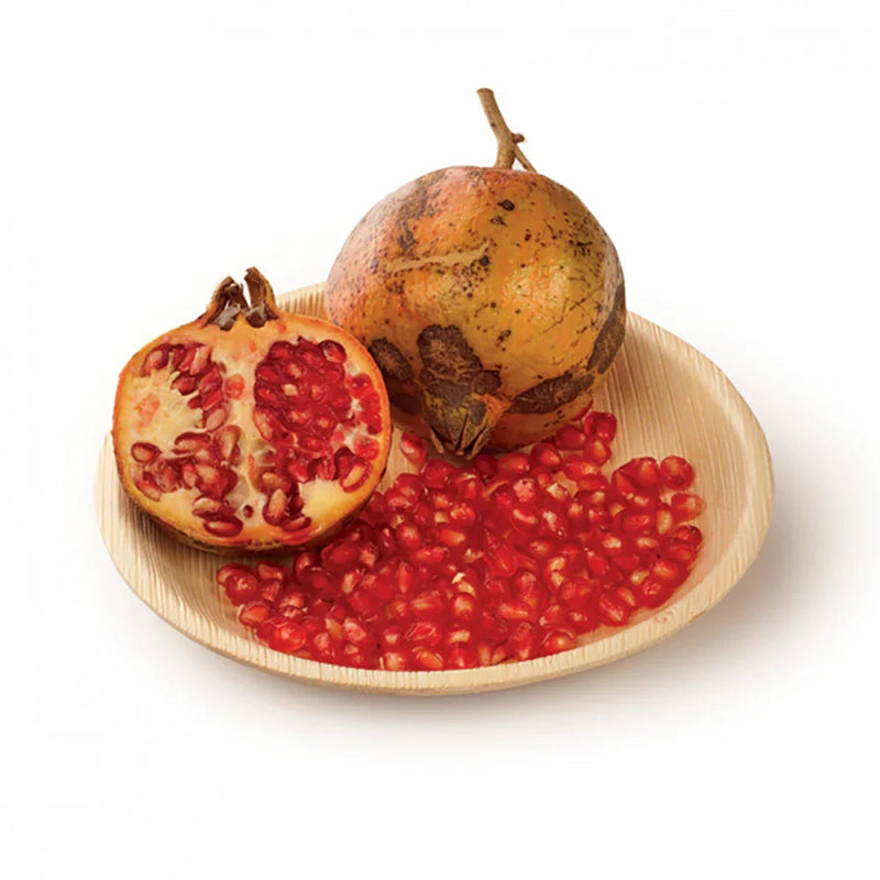 Prato Redondo de Folha de Palmeira com romã e sementes, ideal para serviços de catering, sustentável e decorativo.