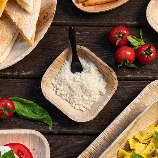 Prato Pequeno Fundo Quadrado de Folha de Palmeira com queijo ralado e outros aperitivos, ideal para catering.
