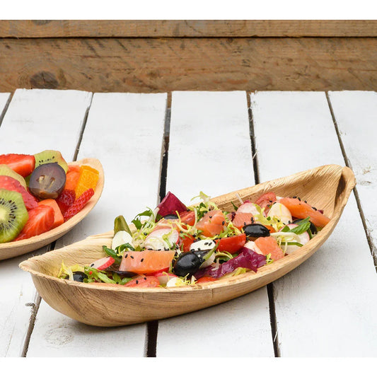Bandeja Canoa Grande Oval de Folha de Palmeira com salada, ideal para serviços de catering e eventos. 25un disponíveis.