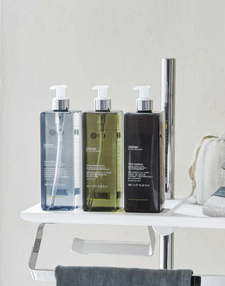 Kit de Amenities Anyah Essentials com três frascos de produtos à vista em prateleira,formato amenities, perfeito para hotéis e alojamentos locais