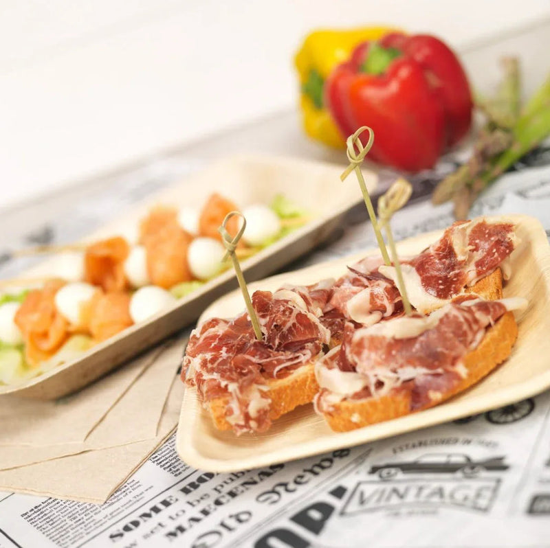 Prato Quadrado de Folha de Palmeira com aperitivos de presunto em prato descartável.