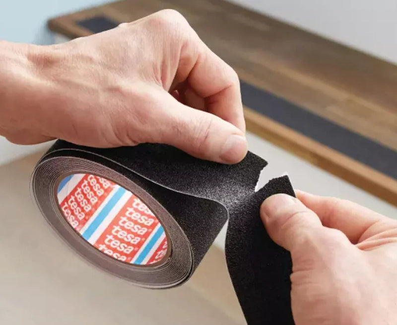 Mãos segurando a Fita Adesiva Anti-Derrapante tesa®, destacando o material resistente e a versatilidade para segurança.