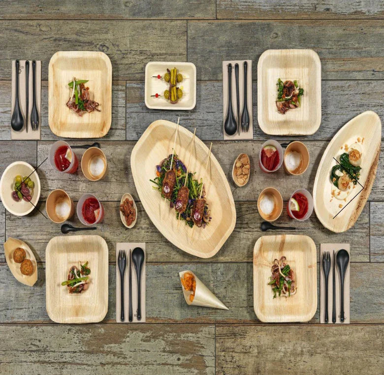 Mini Tijela Bowl de Folha de Palmeira com aperitivos e pratos diversos em mesa rústica.
