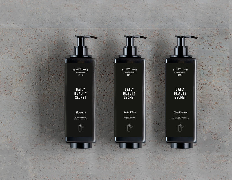 Leite Hidratante Corporal Guest Love Frasco 35ml, frascos de shampoo, condicionador e gel de banho em fundo cinza, perfeito para hotéis e alojamento local