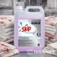 Detergente Máquina da Roupa Skip Profissional Mantelerias 5L em embalagem de 5 litros com toalhas sujas ao fundo.