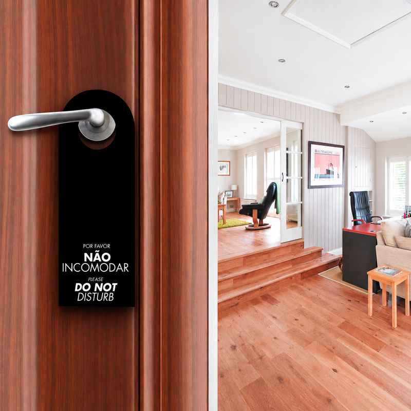 Aviso Pendurável de Não Incomodar colocado na porta de um hotel, com interior elegante e moderno ao fundo.
