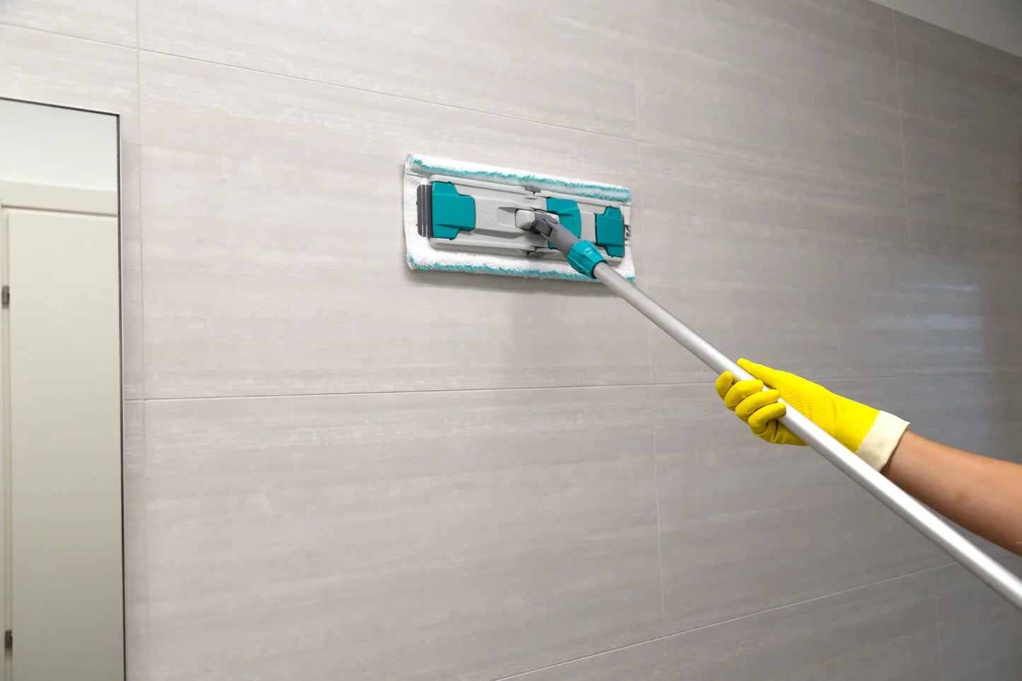 Empregada de limpeza utilizando o Kit Portátil de Balde e Espremedor para Mopas Húmidas TTS na lavagem de paredes