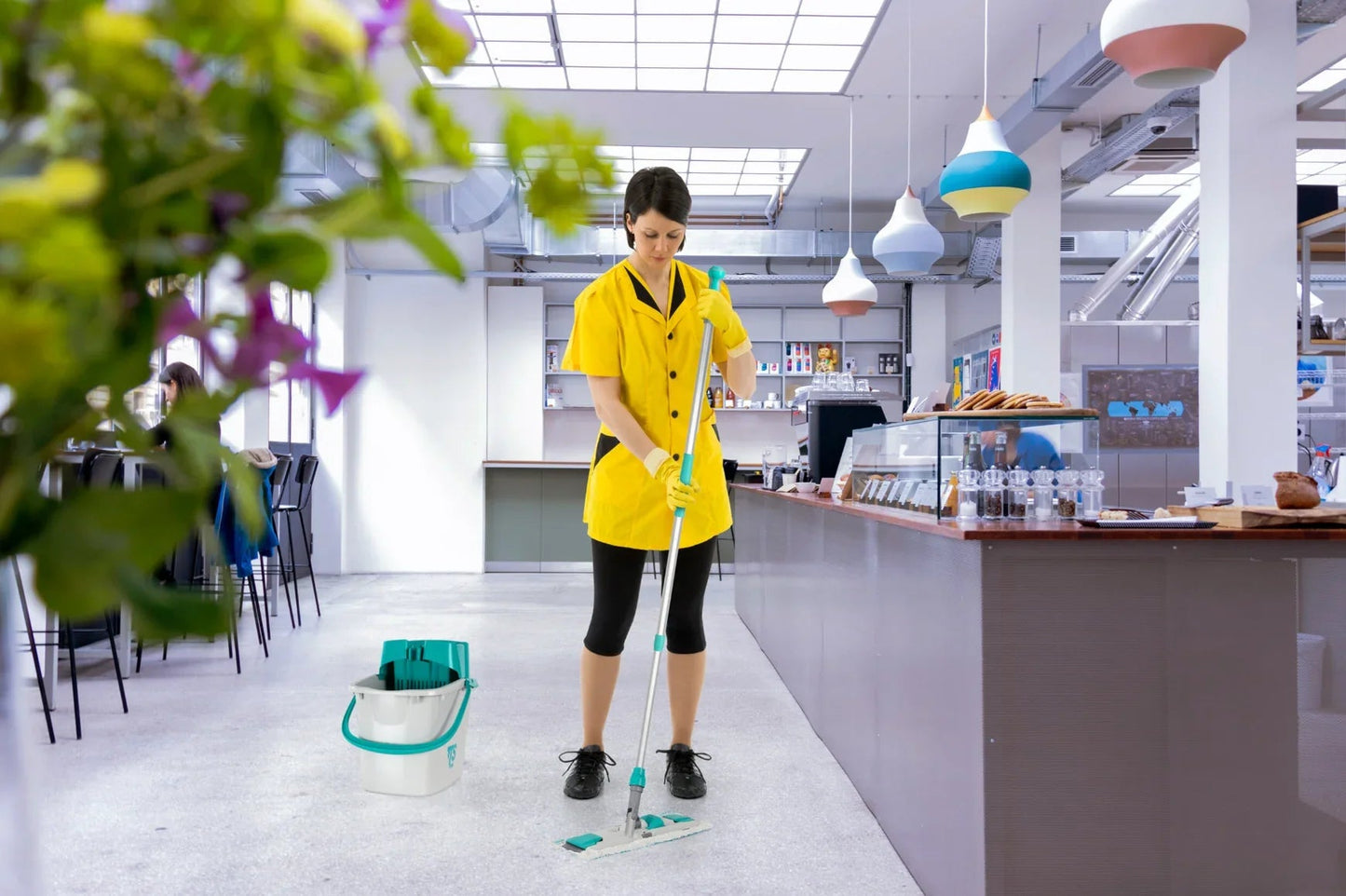 Empregada de limpeza utilizando o Kit Portátil de Balde e Espremedor para Mopas Húmidas TTS na lavagem de pavimentos